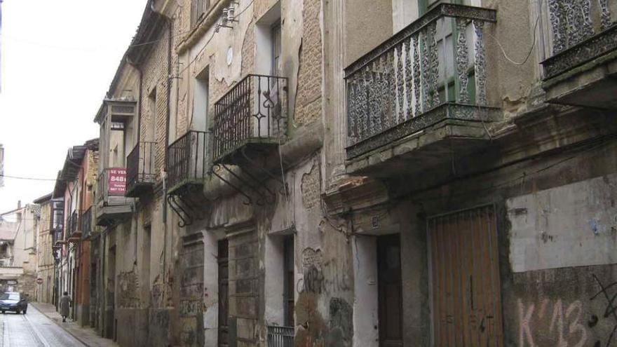 Street facade with peeling render, wrought-iron balconies and graffiti, starting photo for Mix&Design facade renovation